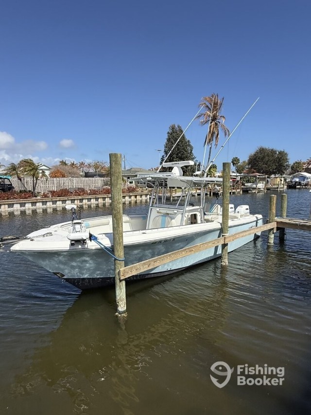 A fishing boat docked by wooden posts on a sunny day.