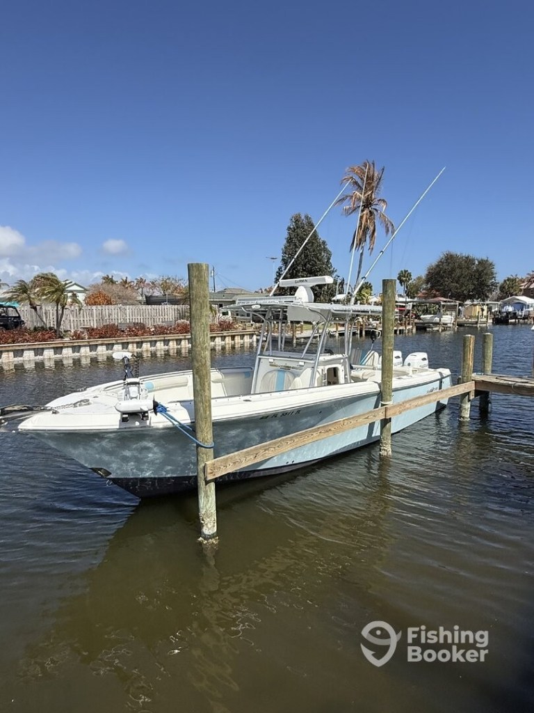 A fishing boat docked by wooden posts on a sunny day.